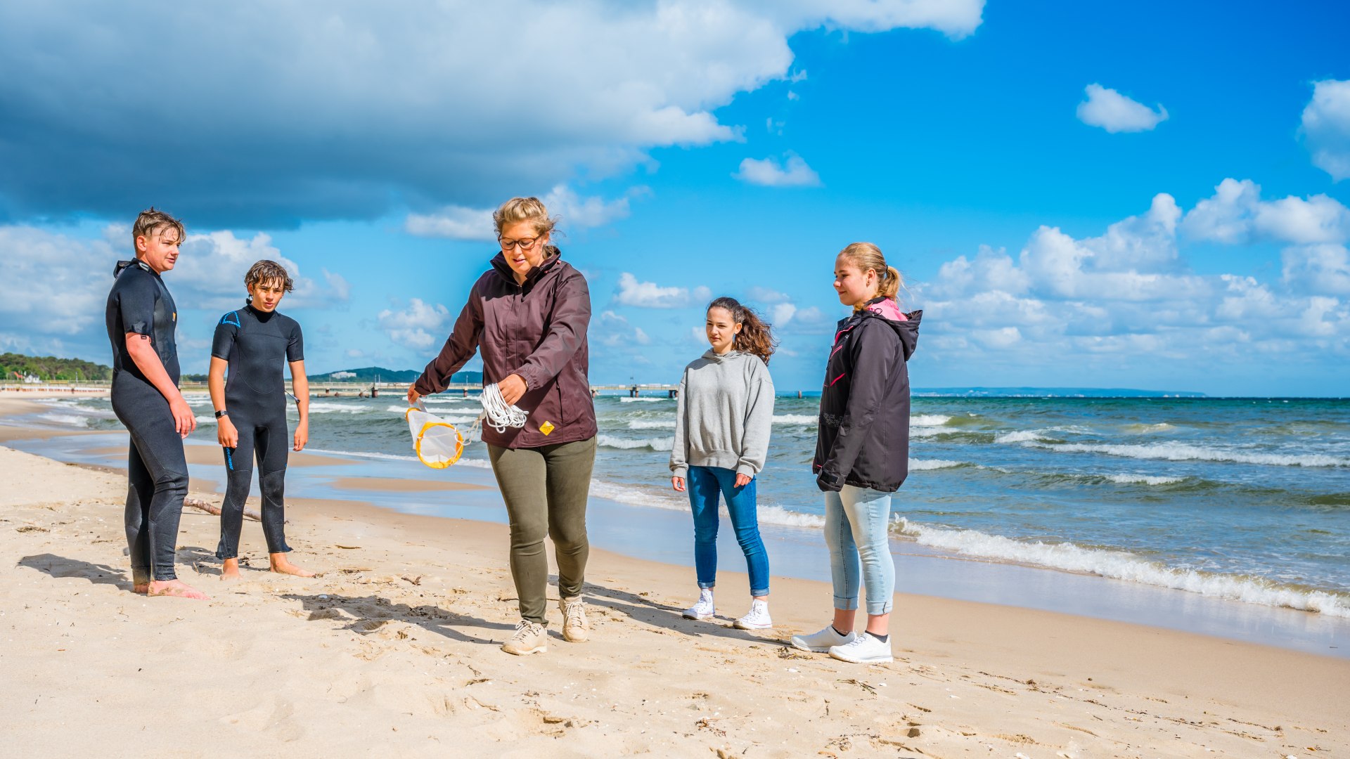 Alexandra Hanusch in action - even as a child she wanted to be a marine biologist., © TMV/Tiemann A marine biologist shows a small trawl net for catching samples from the Baltic Sea. The children around her watch intently.