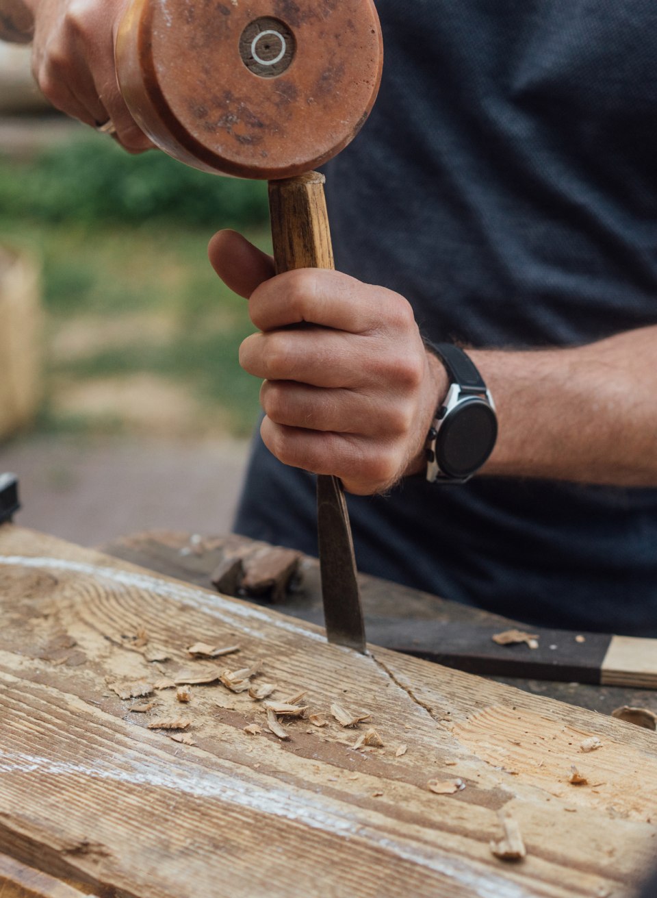 Dexterity: Andreas uses a mallet and chisel to shape a fish on the surface of the old piece of wood during the sculpting workshop., © TMV/Petermann A person shapes something into a large piece of wood with a mallet and chisel during the sculpting workshop