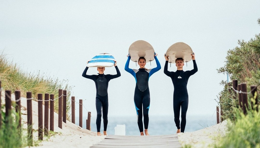 Participants of the surf camps come up the beach walk with their surfboards., © TMV/Felix Gänsicke