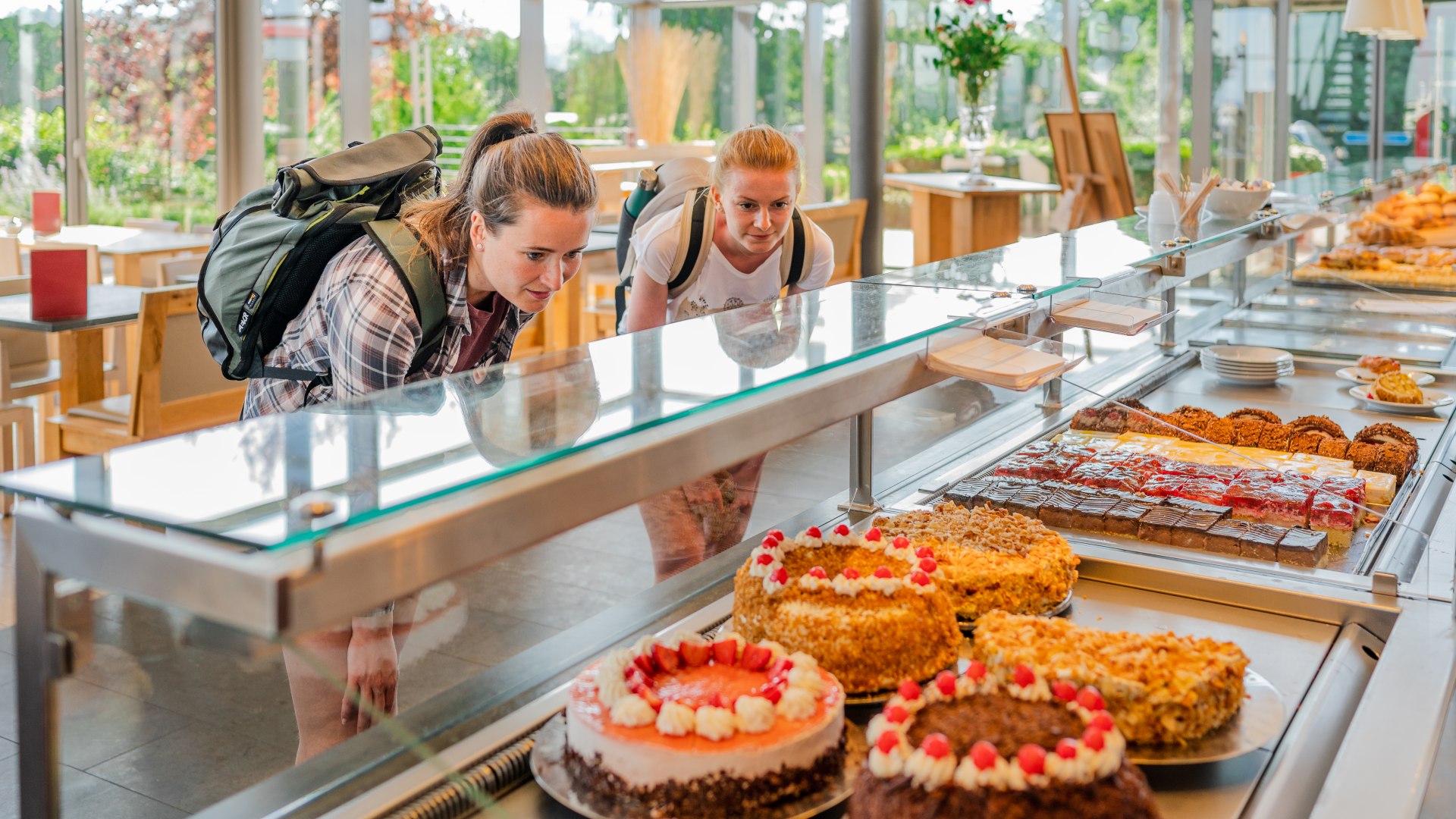 Two women look through the display case at a cake buffet at the bakery