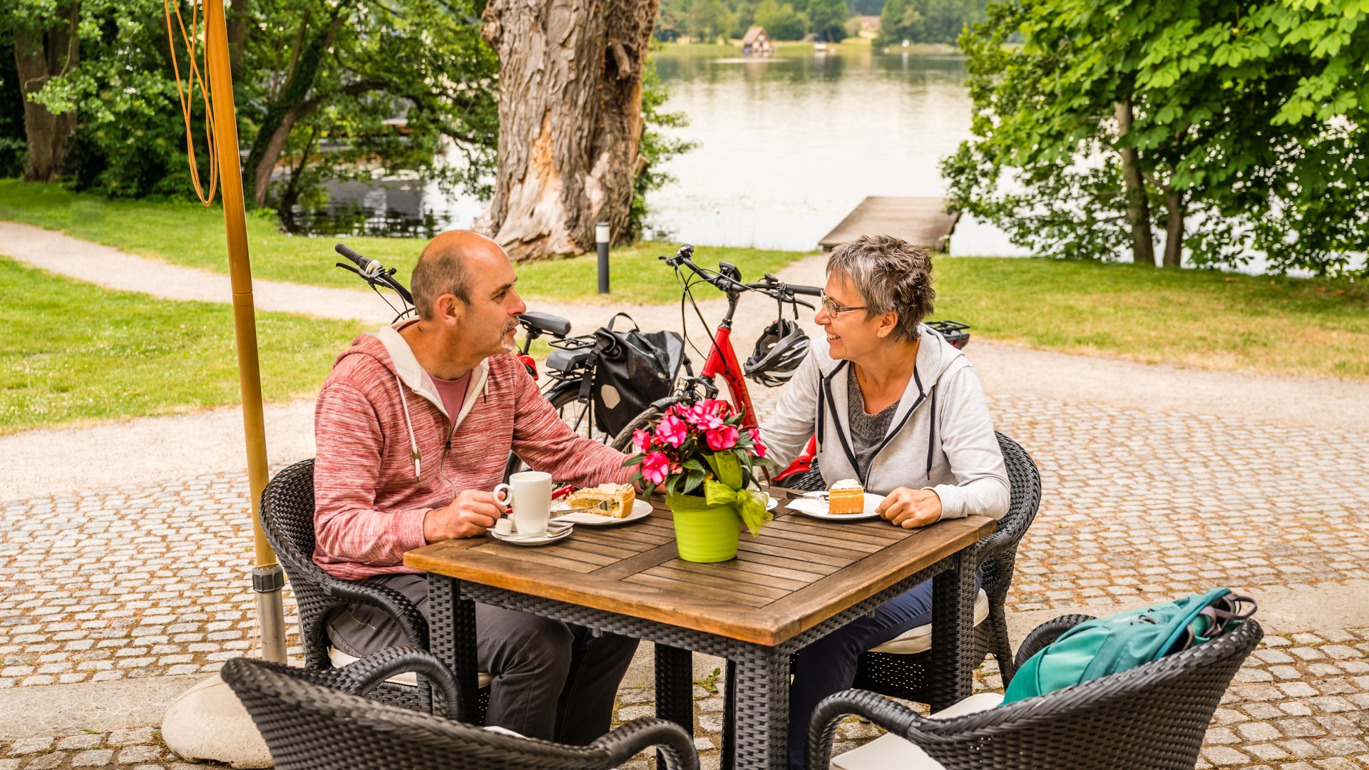 A couple for coffee and cake in front of Mirow Castle and the lake in the background