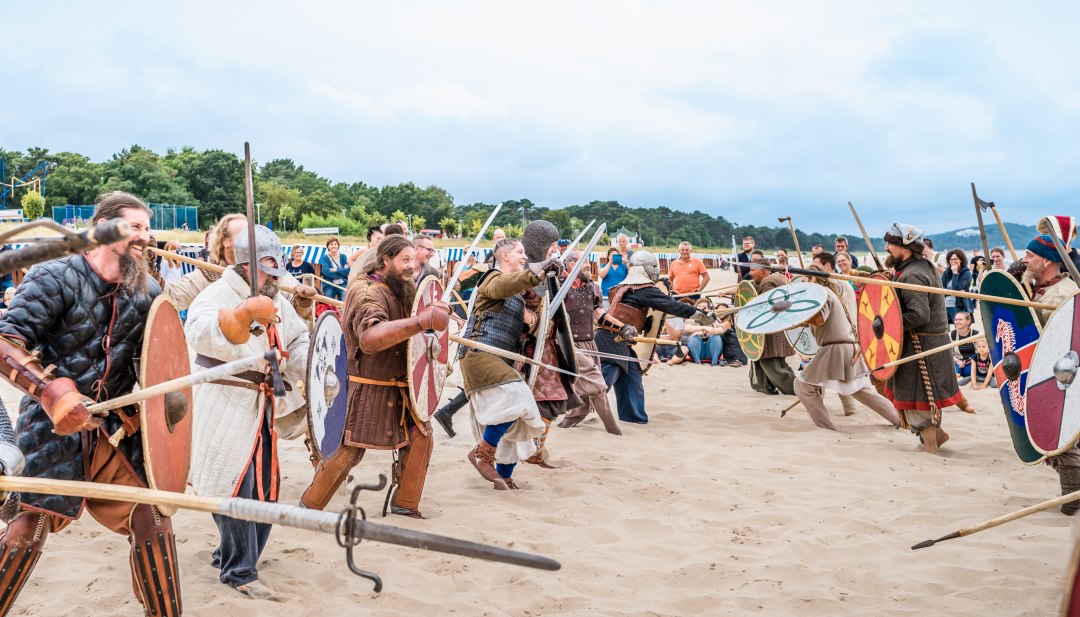Ludzie przebrani za wikingów biegną do siebie na plaży w Göhren
