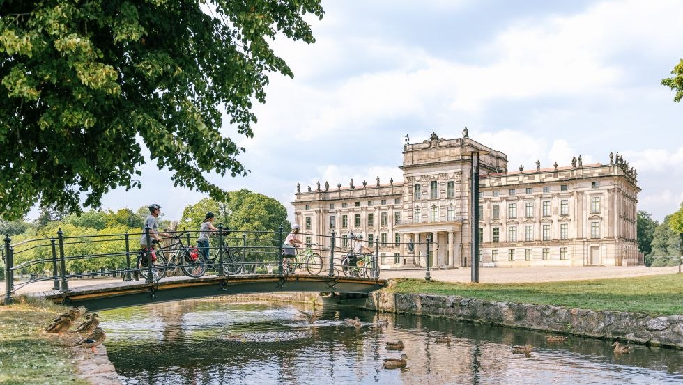 A family with bicycles crosses the bridge with canal at Ludwigslust Castle