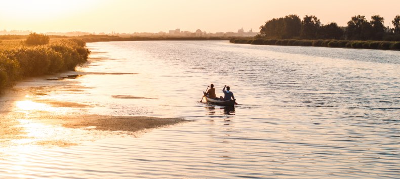 Een rustige avond op het water: twee mensen peddelen bij zonsondergang door de brede wateren van West-Pommeren, omringd door natuur en stilte.