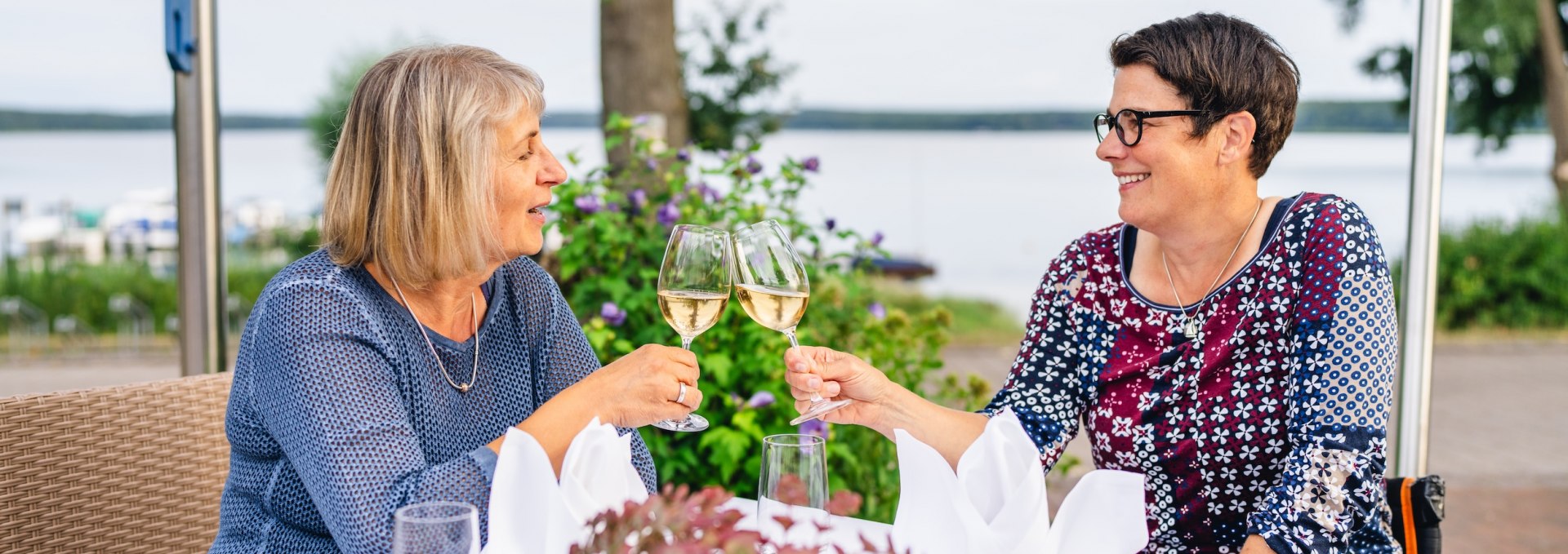 A toast is made at a table with two women and a champagne glass each.