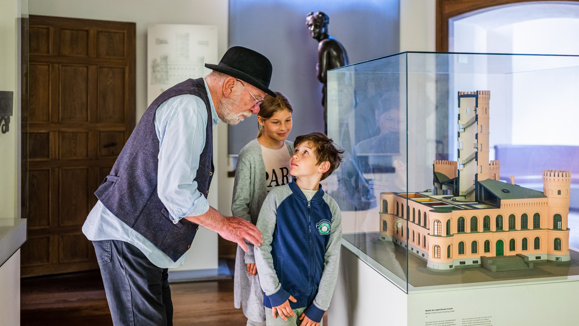 Children stand with the tour guide in front of the model of Granitz Castle