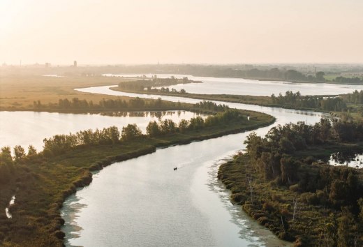 A couple paddles together in a canoe across the river Peene in Mecklenburg-Western Pomerania. The picture shows the vastness of the vacation region of Western Pomerania.