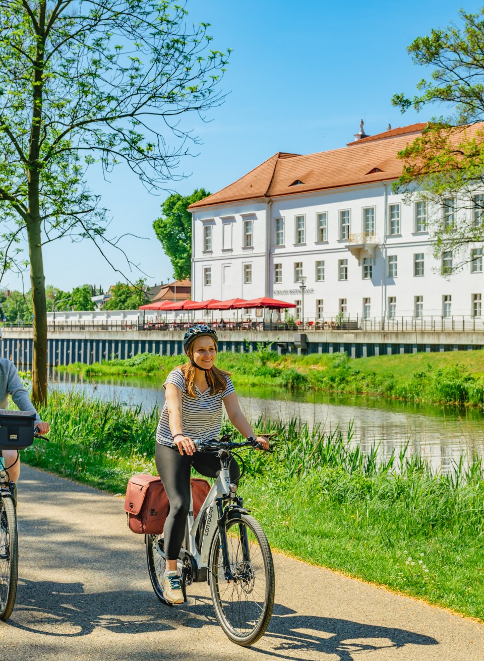 Oranienburg ma zamek i ścieżkę rowerową tuż nad wodą, © TMV/Tiemann Matka i córka na rowerze obok pałacu Oranienburg